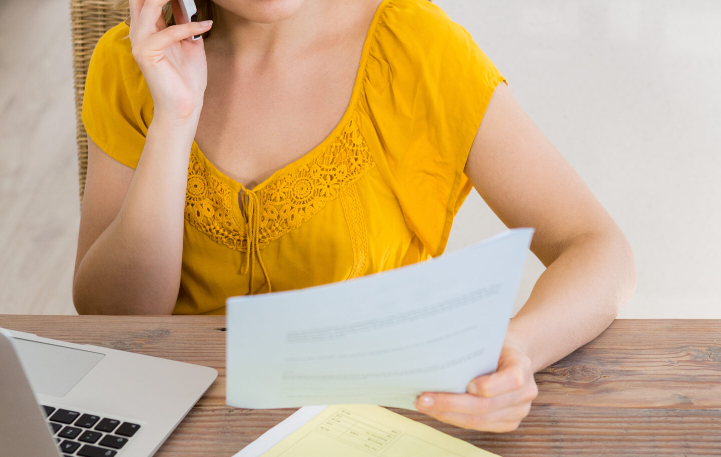 Woman talking mobile phone while looking bill kitchen
